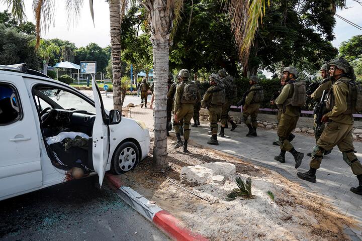 Израильские солдаты проходят мимо тела мужчины в автомобиле, убитого во время массовой атаки боевиков ХАМАС из сектора Газа на город Сдерот, южный Израиль, 7 октября 2023 года. Фото: Reuters